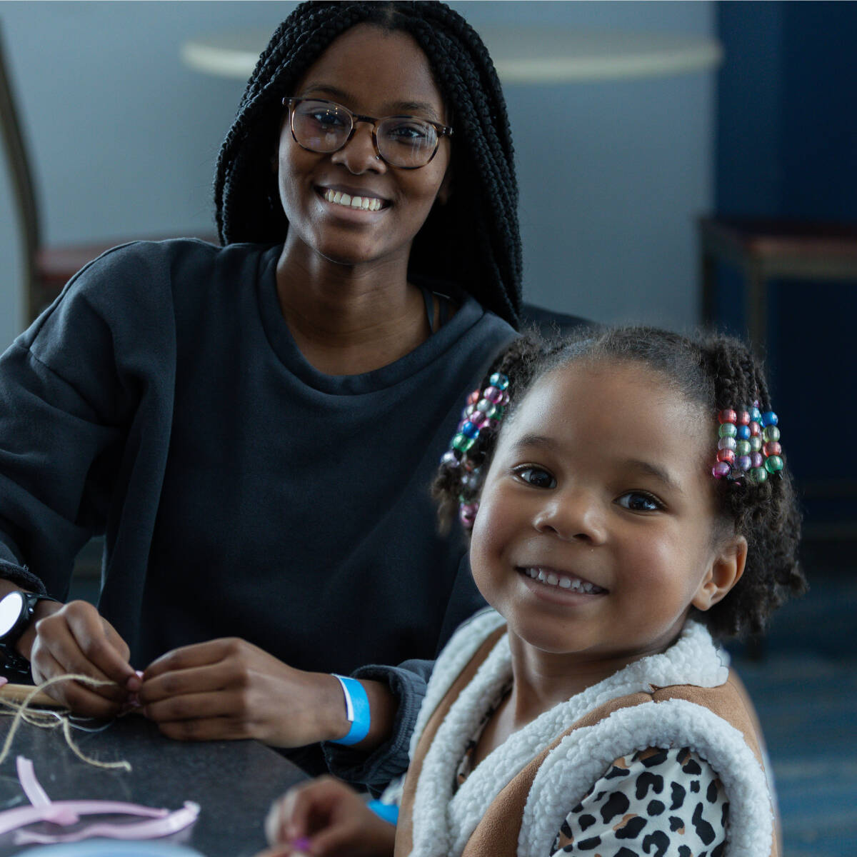 A student and a child smiling and working on a craft